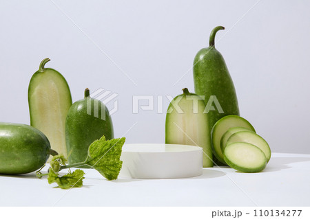Few halves and round slices of winter melon are decorated. A podium with empty space for cosmetic product advertising. Winter melon (Benincasa hispida) is a vegetable with low carb Few halves and round slices of winter melon are decorated. A podium with empty space for cosmetic product advertising. Winter melon (Benincasa hispida) is a vegetable with low carb 110134277