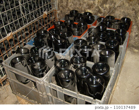 wine dusty bottles upside down in a box for storing and brewing wine. Wine cellar equipment. The process of making expensive French wine. Dust on a Dark Glass Bottle. 110137489