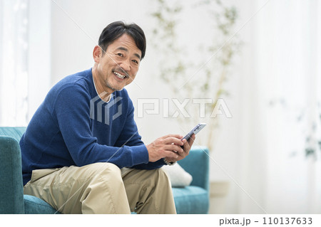 スマートフォンを持った笑顔の50代半ばの男性 110137633