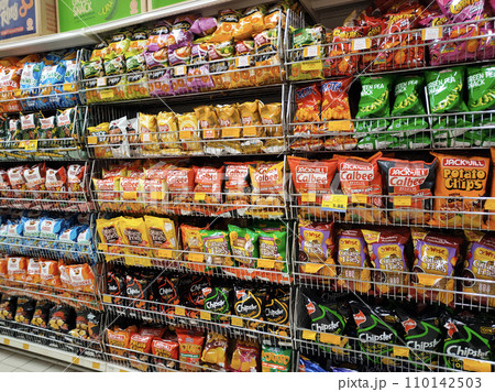 MELAKA, MALAYSIA -APRIL 19, 2022: Selective focused on packed miscellaneous brand junk foods and snacks on the rack and display for sale in the supermarket. Each has its own price tag. MELAKA, MALAYSIA -APRIL 19, 2022: Selective focused on packed miscellaneous brand junk foods and snacks on the rack and display for sale in the supermarket. Each has its own price tag. 110142503