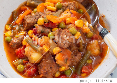 Beef stew with potato, green beans, carrot, peas and corn, in gray bowl, horizontal, closeup Beef stew with potato, green beans, carrot, peas and corn, in gray bowl, horizontal, closeup 110143181