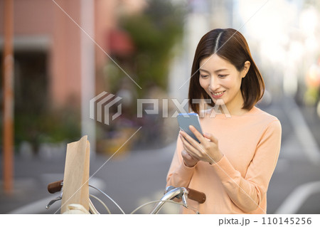 自転車で買い物に行くミドルの女性 110145256