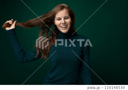 Portrait of a charismatic young woman with brown eyes wearing a green turtleneck 110148530