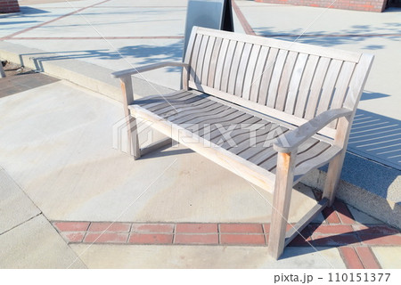 明るい公園に置いてあるベンチ 110151377
