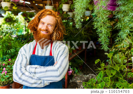 young redhaired ginger bearded man in apron working in the garden or plantation young redhaired ginger bearded man in apron working in the garden or plantation 110154703