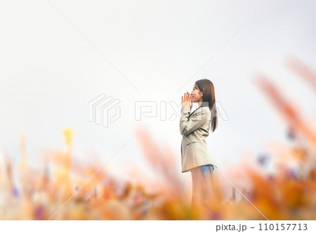 草原で呼ぶ女性 110157713