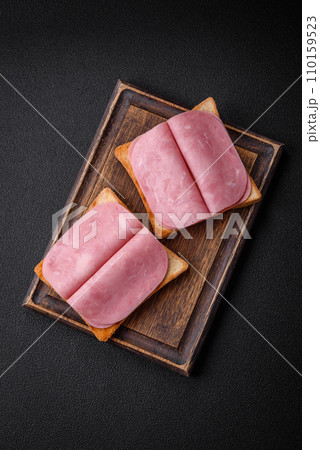 Delicious sandwich with toast bread, ham, tomatoes, salt and spices Delicious sandwich with toast bread, ham, tomatoes, salt and spices 110159523