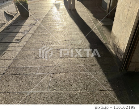 夕暮れ時の石畳に映る影 110162198