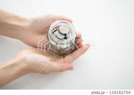 手に収まる貯金、コインが詰まった透明な瓶 手に収まる貯金、コインが詰まった透明な瓶 110162750