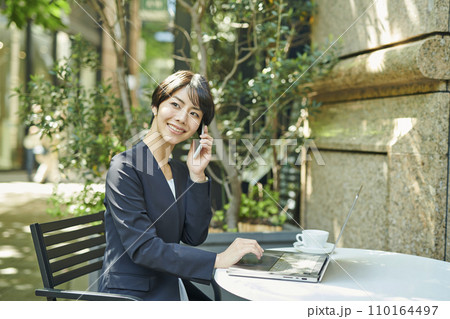 テラス席で電話をする30代女性会社員 テラス席で電話をする30代女性会社員 110164497