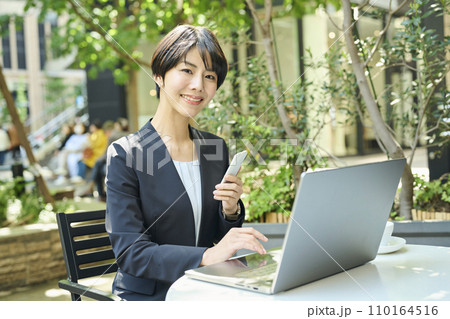 テラス席で仕事をする30代女性会社員 110164516