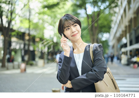 街中で電話をする30代女性会社員,笑顔 街中で電話をする30代女性会社員,笑顔 110164771