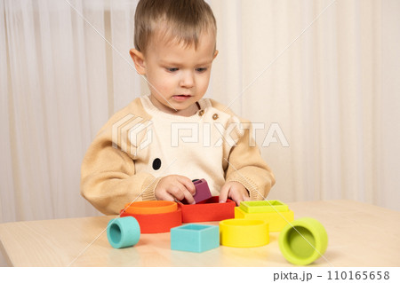 A two-year-old boy plays with wooden toys to develop logic and motor skills 110165658