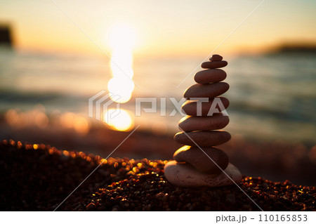 Cairn lies on the seacoast in the rays of the setting sun 110165853