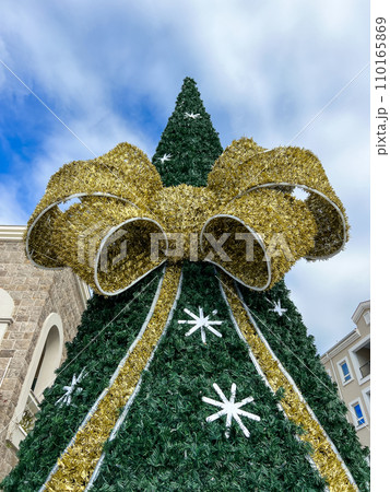 Artificial Christmas tree decorated with a huge fluffy bow Artificial Christmas tree decorated with a huge fluffy bow 110165869