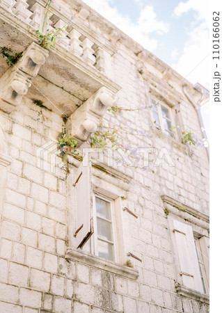 Open white wooden shutters on the windows of an ancient stone house Open white wooden shutters on the windows of an ancient stone house 110166062