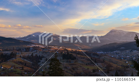 Late autumn mountain pre sunset scene with snow covered tops in far. Picturesque traveling, seasonal, nature and countryside beauty concept scene. Carpathians, Ukraine. 110166334