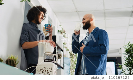 Colleagues laughing on coffee break, enjoying conversation and joking around in open space shared office. Coworkers relaxing at work, talking to each other in modern workplace. Colleagues laughing on coffee break, enjoying conversation and joking around in open space shared office. Coworkers relaxing at work, talking to each other in modern workplace. 110167125