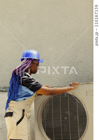 Competent technician dismantling hvac system front grill in order to start fixing faulty internal parts. Expert electrician contracted by business owner to do maintenance on outdoor air conditioner 110167139
