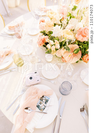 Fujifilm Instax mini instant camera lies on a set table next to plates and photographs 110174073