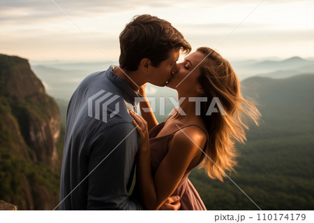 Romantic young couple kissing passionately at sunset with mountains background by Generative Ai 110174179