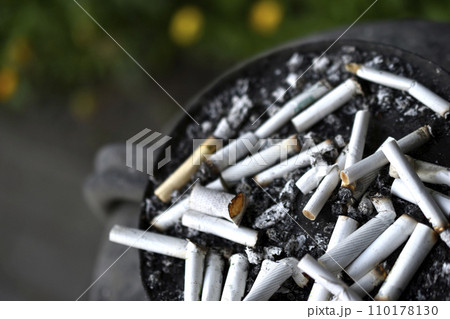 An ashtray for cigarette butts on the street. Smoked cigarettes in the trash. 110178130