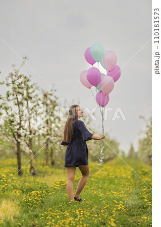 girl with balloons in a young garden 110181573