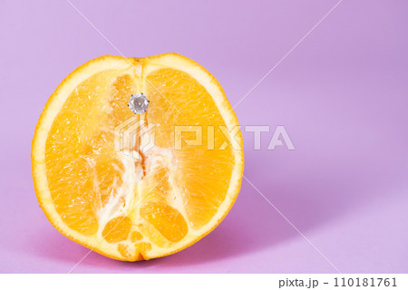 Intimate piercing. Minimal piercing concept. Orange with inserted iron decoration, piercing Intimate piercing. Minimal piercing concept. Orange with inserted iron decoration, piercing 110181761