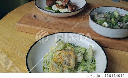 Table setting. Ready-made dishes, meat, fish and vegetable salad on the table, close-up of a dish from a restaurant, three plates with appetizing food. Healthy food. Nutrition concept 110184013