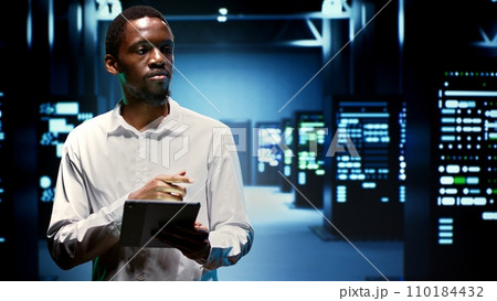 IT administrator in hardware room housing server rackmounts, storage devices and networking units providing vast amounts of computing resources. Supervisor doing equipment maintenance IT administrator in hardware room housing server rackmounts, storage devices and networking units providing vast amounts of computing resources. Supervisor doing equipment maintenance 110184432