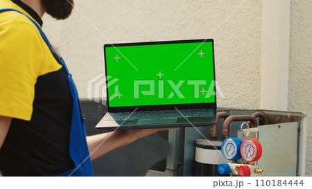 Technician ordering new components on chroma key laptop for damaged air conditioner after finishing investigation. Mechanic looking online for condenser replacement parts, comissioned by customer Technician ordering new components on chroma key laptop for damaged air conditioner after finishing investigation. Mechanic looking online for condenser replacement parts, comissioned by customer 110184444
