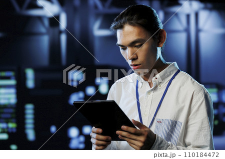 Tech support worker between server room equipment providing processing resources for businesses worldwide. Skillful developer fixes data center supercomputers used for managing massive databases Tech support worker between server room equipment providing processing resources for businesses worldwide. Skillful developer fixes data center supercomputers used for managing massive databases 110184472