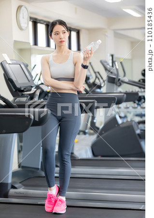 スポーツジムで水分補給をする若い女性 スポーツジムで水分補給をする若い女性 110185436