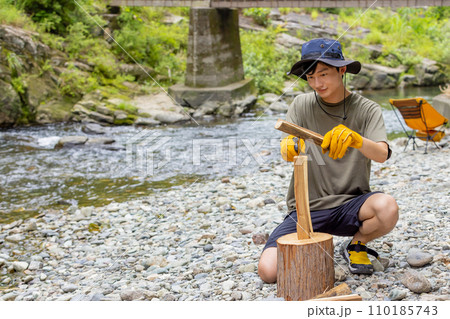 キャンプで薪割りをする男性 110185743