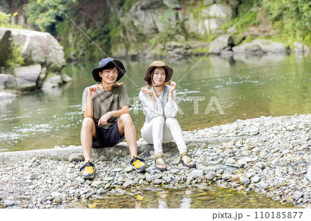 川原で鮎を食べるカップル 川原で鮎を食べるカップル 110185877