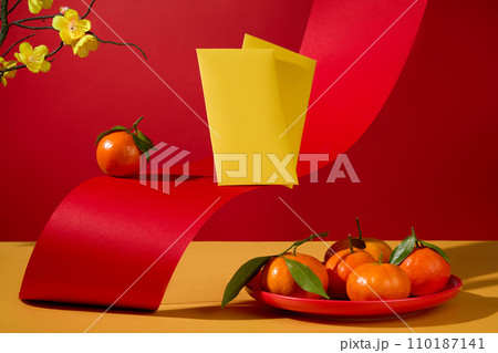 A round dish containing tangerines decorated with yellow envelopes. Each country has different unique traditional customs during the Lunar New Year A round dish containing tangerines decorated with yellow envelopes. Each country has different unique traditional customs during the Lunar New Year 110187141