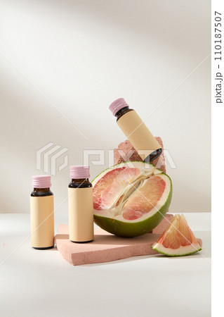 Scene for advertising and branding product with ingredient from pomelo. Front view of medicine bottles with pomelo slices displayed on pink bricks on white background Scene for advertising and branding product with ingredient from pomelo. Front view of medicine bottles with pomelo slices displayed on pink bricks on white background 110187507