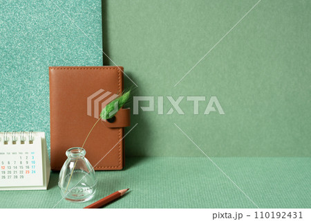 Diary notebook, calendar, vase of plant, colored pencil on desk. green wall background. planning office supply 110192431