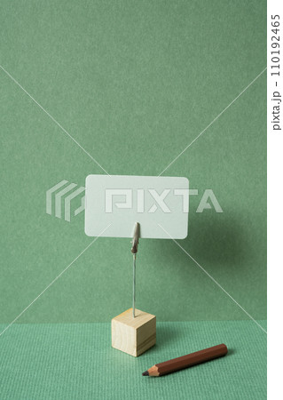 Memo pad with holder and colored pencil on desk. green wall background. copy space 110192465