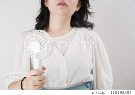 ハンディファンを使う若い女性 110192802