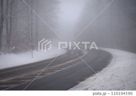 Bad weather driving - foggy hazy country road. Motorway - road traffic. Winter time. Autumn - fall. Snow and frost on the road in winter. Bad weather driving - foggy hazy country road. Motorway - road traffic. Winter time. Autumn - fall. Snow and frost on the road in winter. 110194590