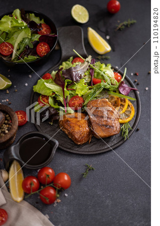 pieces of Organic grilled Tuna Steak on black ceramic serving dish with salad on a table pieces of Organic grilled Tuna Steak on black ceramic serving dish with salad on a table 110194820