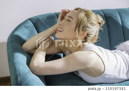 ソファに横になる茶髪の若い女性のバストアップのポートレート ソファに横になる茶髪の若い女性のバストアップのポートレート 110197381