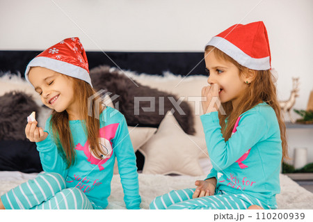 Adorable twins in christmas hats playing in bed 110200939