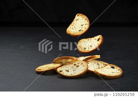 Falling bruschetta crackers, round bread croutons isolated on black background with copy space, full depth of field 110201250