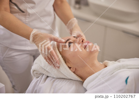 perfect skin, head massage, Cosmetology. Beautiful female gets facial massage in beauty clinic, lying on back, getting massage to lift face, beauty concept, skin care, spa concept 110202767