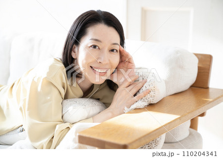 ソファーで微笑む女性 110204341