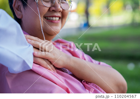 Asian careful caregiver or nurse hold the patient hand and encourage the patient in a wheelchair.  Concept of happy retirement with care from a caregiver and Savings and senior health insurance. 110204567