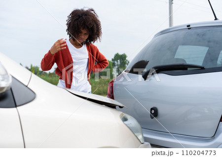 Half Thai African driver check for damage after a car accident before taking pictures and sending insurance. Online car accident insurance claim after submitting photos and evidence to an insurance. 110204773