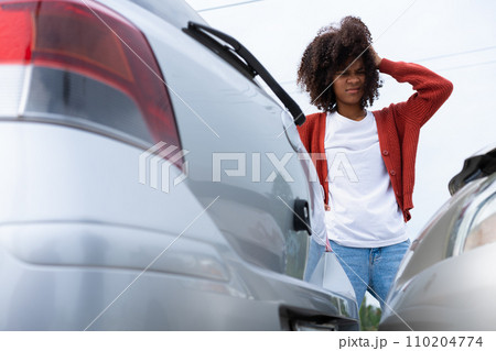 Half Thai African driver check for damage after a car accident before taking pictures and sending insurance. Online car accident insurance claim after submitting photos and evidence to an insurance. 110204774